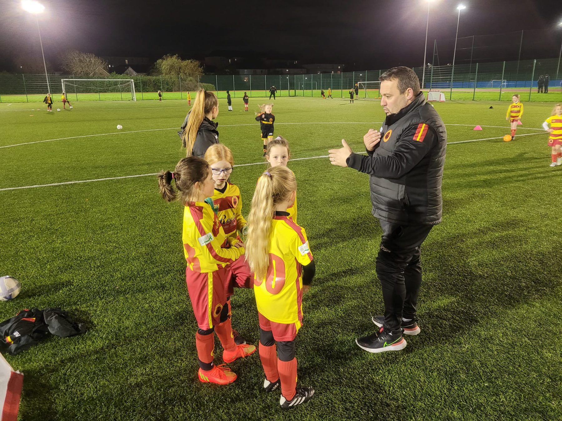 A Rossvale coach talking to two young players at training